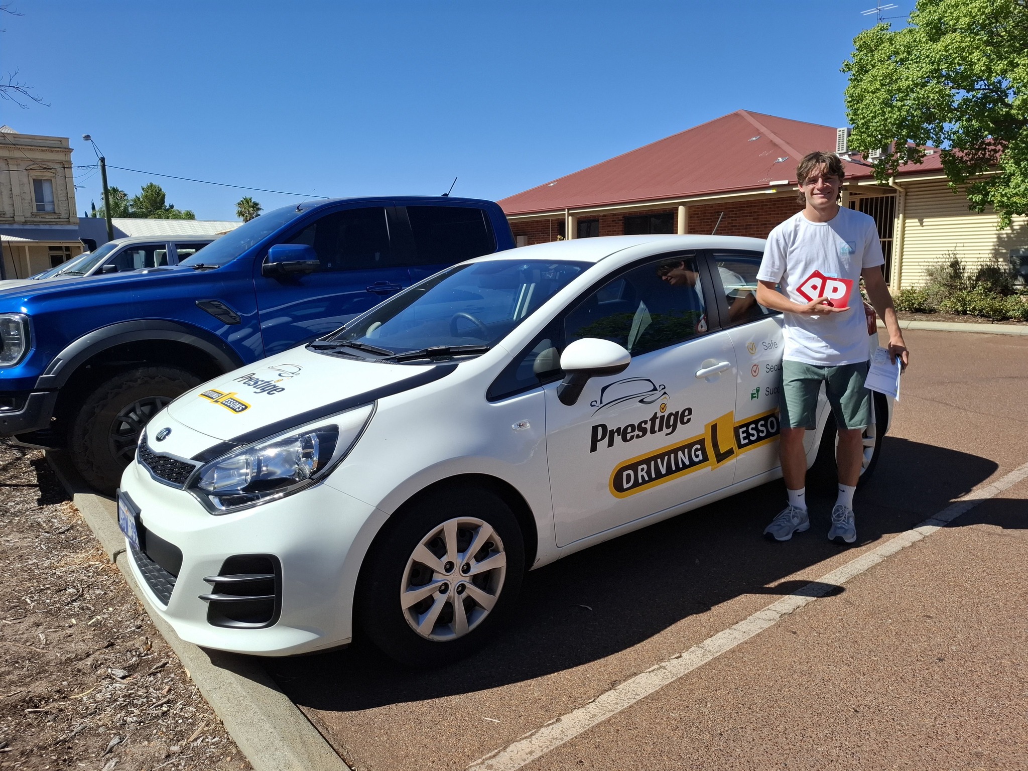 Happy student holding P plates after passing with DJ